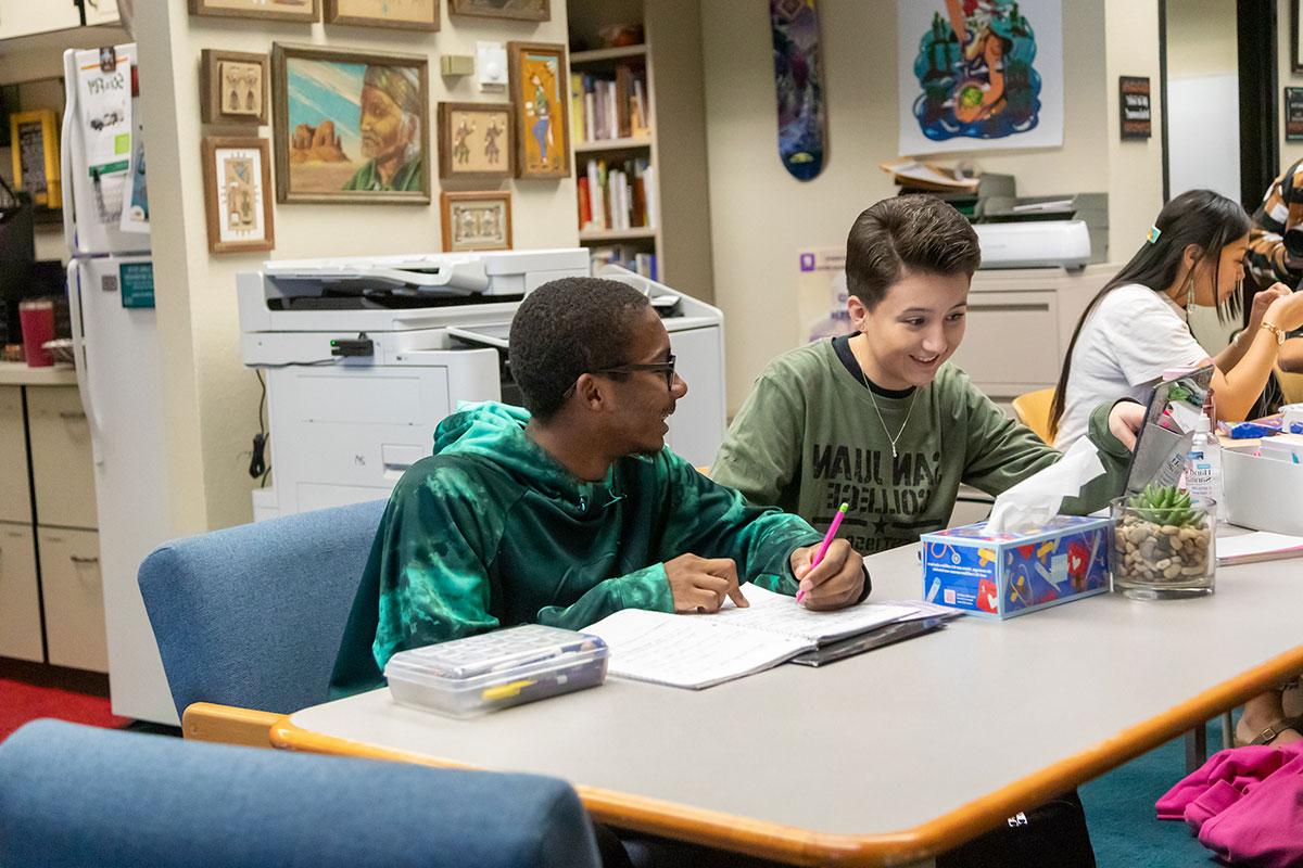 Two students sitting together in front of a laptop doing a training