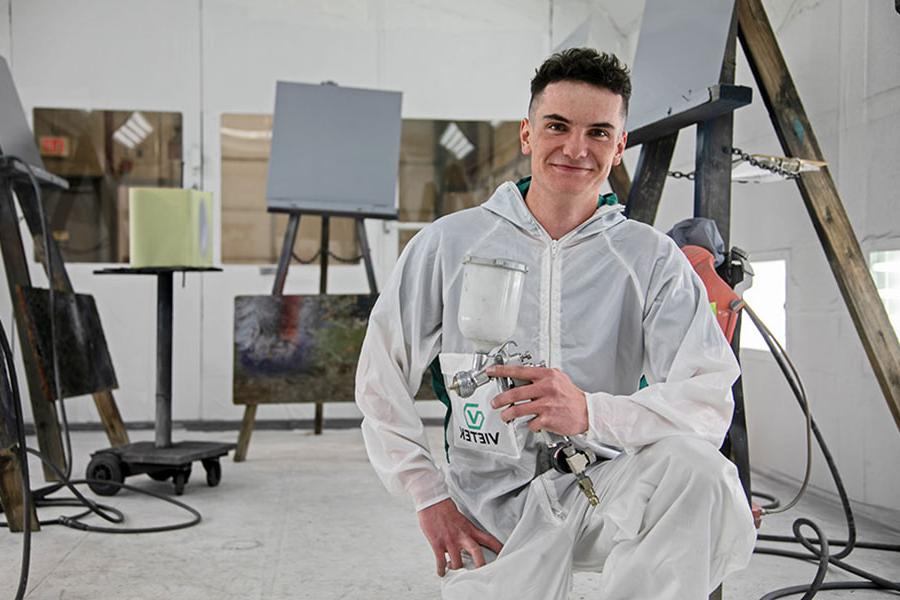 火博体育 student holding a paint sprayer in the 汽车的身体 paint booth